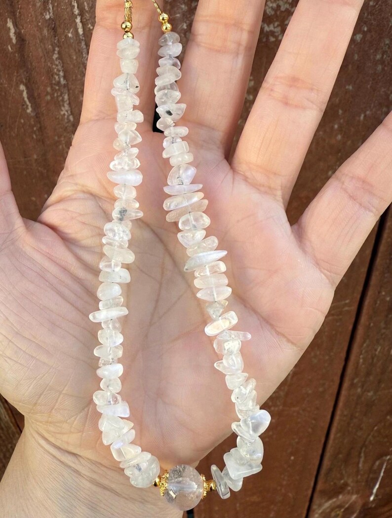 Puede incluir: Un collar con peque&ntilde;as piedras irregulares de cuarzo transparente. El collar tiene un cierre dorado y una cuenta de cuarzo transparente m&aacute;s grande y redonda en el centro. Las piedras son de color claro y parecen pulidas.