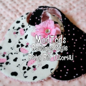 May include: Two baby bibs with a pink flower and text. One bib features a cow print on white fabric, the other has black fabric with pink polka dots. The text reads "ModTods Boutique Style Baby Bib Tutorial."
