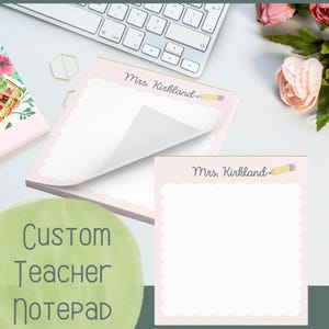 May include: Pink custom teacher notepad with a scalloped edge and the name "Mrs. Kirkland" printed at the top. A yellow pencil graphic is next to the name. The notepad is on a white desk with a keyboard and flowers.