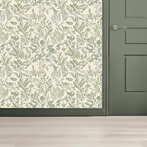 Peut inclure: Papier peint floral avec un motif répété de feuilles et de fleurs vertes et grises sur un fond crème. Le papier peint est à côté d'une porte verte avec une poignée argentée.