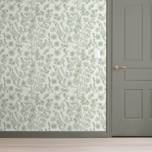 Puede incluir: Una pared cubierta con papel pintado floral con un diseño verde claro. El papel pintado presenta un patrón repetitivo de flores y hojas. Una puerta gris con manija dorada está a la derecha.
