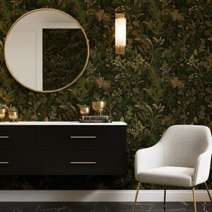 Op de afbeelding: Een modern interieur met een zwarte kast, gouden accenten en een ronde spiegel. De muur is voorzien van donkergroen bloemenbehang. Rechts staat een lichtgrijze stoel met gouden poten. Decoratieve gouden plantenbakken en een wandlamp maken het decor compleet.
