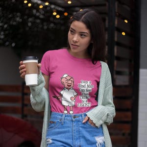 Puede incluir: Una camiseta rosa con un personaje de dibujos animados y el texto "Even a Blind Man Can See That TRUMP is a FASCIST!". El gráfico está en la parte delantera de la camiseta.