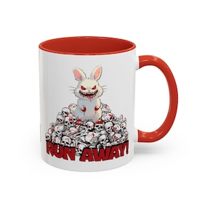 May include: White ceramic mug with a red interior and handle. The mug features a cartoon illustration of a menacing white rabbit covered in blood, sitting atop a pile of skulls. The words "RUN AWAY!" are printed in red.