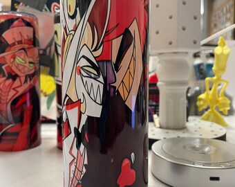May include: A tall, cylindrical tumbler featuring colorful cartoon character designs. The tumbler has a black and red gradient background with cartoon characters in white, red, and black. The tumbler is likely made of stainless steel.