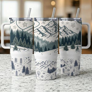 May include: Three stainless steel tumblers with a white background and a mountain scene with trees and a winding path. The tumblers have lids and straws.