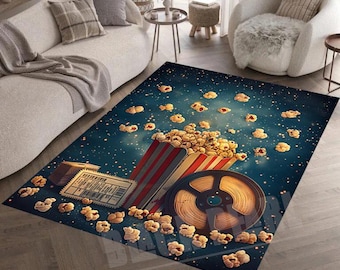May include: A blue and white rug with a movie theme. The rug features a popcorn bucket, a film reel, and popcorn scattered across the rug. The rug has a starry night sky background.