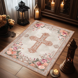 Puede incluir: Una alfombra rectangular con fondo crema y un gran dise&ntilde;o de cruz ornamentada en el centro. La alfombra est&aacute; bordeada con motivos florales en tonos rosa, melocot&oacute;n y verde. Las dimensiones de la alfombra son de aproximadamente 152 cm por 102 cm.