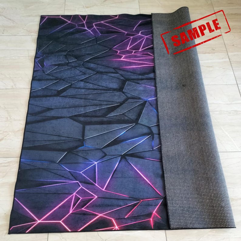 Puede incluir: Una alfombra rectangular con un dise&ntilde;o geom&eacute;trico en tonos grises, azules y morados. El patr&oacute;n presenta formas angulares con l&iacute;neas rosas y moradas de estilo ne&oacute;n. La alfombra est&aacute; parcialmente enrollada, revelando un respaldo gris texturizado. La palabra "SAMPLE" est&aacute; estampada en la alfombra.