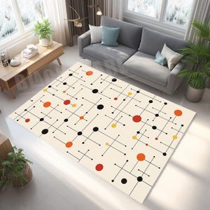 May include: Cream-colored rectangular area rug with a mid-century modern design. The rug features a pattern of black lines, circles in red, orange, and yellow. The rug is in a living room setting with a gray sofa and wooden furniture.
