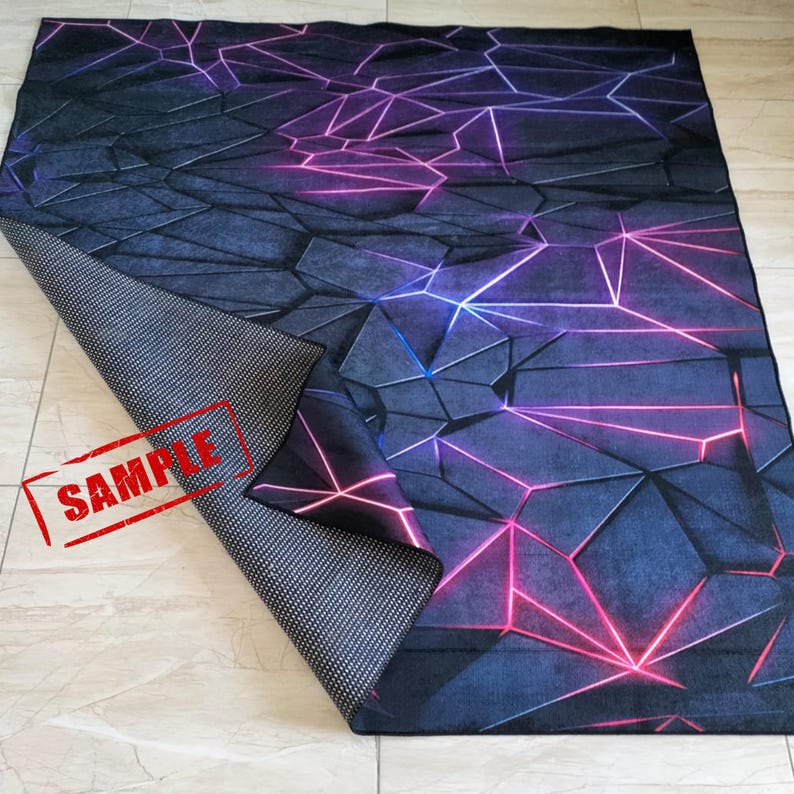 Puede incluir: Una alfombra rectangular con un dise&ntilde;o geom&eacute;trico. La alfombra presenta un fondo azul oscuro y gris con un patr&oacute;n de formas interconectadas y l&iacute;neas de ne&oacute;n rosas y azules. La parte inferior de la alfombra es negra con puntos blancos.