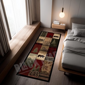Puede incluir: Alfombra rectangular con un diseño de patchwork con cabañas, osos, pinos y patrones de cuadros en tonos de rojo, verde y marrón. La alfombra está colocada sobre un suelo de madera junto a una cama.