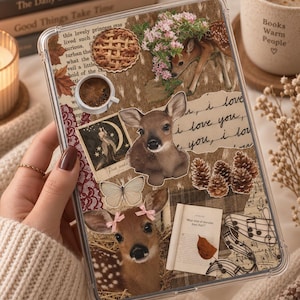 Può includere: Una custodia trasparente per tablet con un collage di immagini a tema boschivo, tra cui due cervi, una torta, una tazza di caffè, pigne, una farfalla, una pagina di libro con testo, note musicali e scritte a mano con I love you.