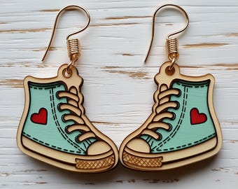 May include: A pair of wooden earrings shaped like light blue sneakers with red hearts. The earrings have gold hooks.
