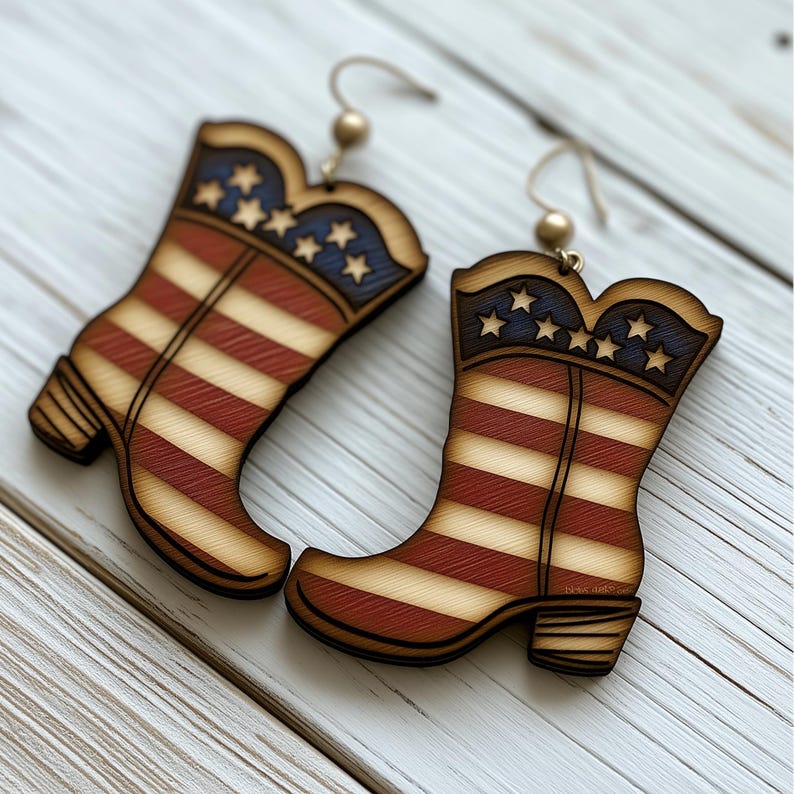 Op de afbeelding: Een paar houten oorbellen in de vorm van cowboylaarzen met een Amerikaans vlagontwerp. De laarzen zijn rood, wit en blauw met witte sterren aan de bovenkant.
