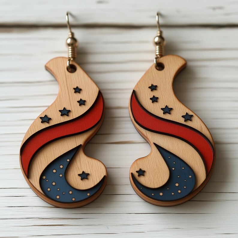 Op de afbeelding: Een paar houten oorbellen met een rood, wit en blauw ontwerp. De oorbellen zijn gevormd als een halve maan met sterren en een rode streep.