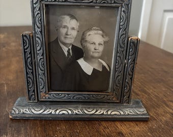 Può includere: Fotografia antica in bianco e nero in una cornice decorativa argentata. La cornice ha un design ornato e un supporto per l'esposizione. La fotografia presenta un ritratto di un uomo e una donna.