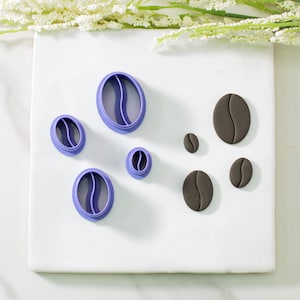 May include: A set of purple cookie cutters shaped like coffee beans, and five brown fondant coffee beans of varying sizes.