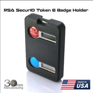 May include: Black RSA SecurID Token & Badge Holder with red and blue accents. The token has a rectangular shape with rounded edges and a slot at the top. The text "RSA SecurID" is visible. The product is 30 mm and made in the USA.