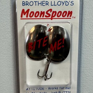 Puede incluir: Un se&ntilde;uelo de pesca plateado con las palabras "Bite Me!" en letras rojas. El se&ntilde;uelo est&aacute; empaquetado en una bl&iacute;ster de pl&aacute;stico transparente con una tarjeta blanca que dice "Brother Lloyd's MoonSpoon.  ATTITUDE - Works for me! No Ifs, Ands, - just BUTTS! www.moonspoons.com"
