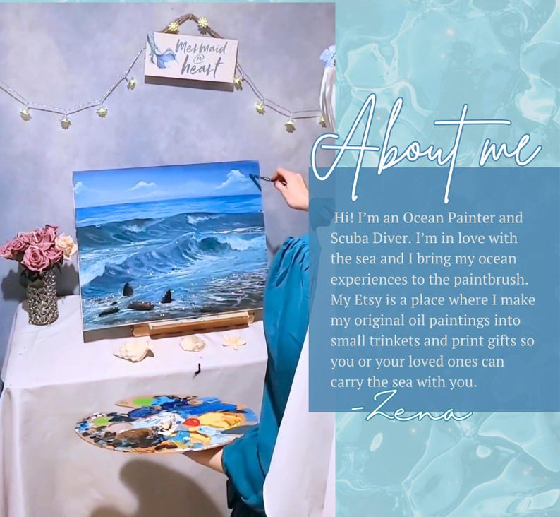 May include: An oil painting of a blue ocean with waves and a cloudy sky on an easel. A wooden palette with colorful paint sits in the foreground. A sign reads Mermaid at heart. Text on the right says About me, Hi! I'm an Ocean Painter and Scuba Diver.