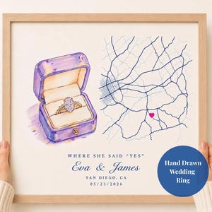 May include: A framed print featuring a watercolor illustration of a purple ring box containing a diamond ring next to a blue line map with a pink heart. Text reads: WHERE SHE SAID "YES", Eva & James, SAN DIEGO, CA, 05/23/2026, and Hand Drawn Wedding Ring.