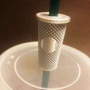 May include: A silver-colored straw holder with a textured design and a circular logo. The holder is attached to a green straw.