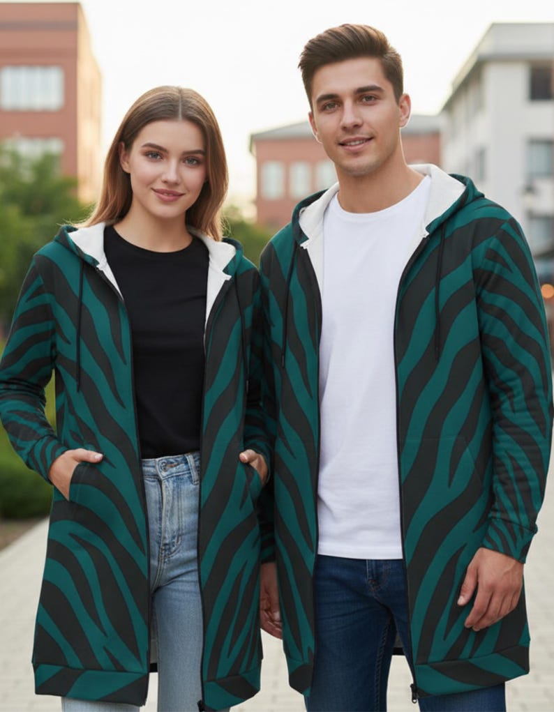 Peut inclure: Deux personnes portant des sweat-shirts &agrave; capuche zipp&eacute;s assortis avec un motif z&eacute;br&eacute; teal et noir. Les sweat-shirts ont une doublure int&eacute;rieure blanche et sont associ&eacute;s &agrave; des jeans et un t-shirt noir ou blanc. L'arri&egrave;re-plan montre des b&acirc;timents et de la verdure.