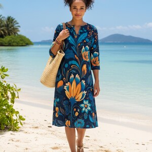 May include: A woman in a navy blue floral dress with orange and blue flowers, three-quarter sleeves, and a V-neck. She carries a straw tote bag and wears sandals on a sandy beach. The dress is knee-length.