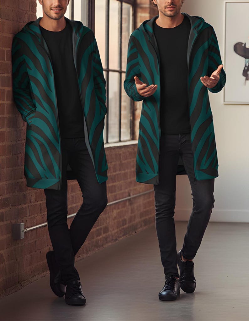 Peut inclure: Longue veste &agrave; capuche avec un motif z&eacute;br&eacute; noir et vert canard. La veste est port&eacute;e sur un t-shirt noir et un pantalon noir. La personne porte des chaussures noires. L'arri&egrave;re-plan comprend un mur de briques et une fen&ecirc;tre.