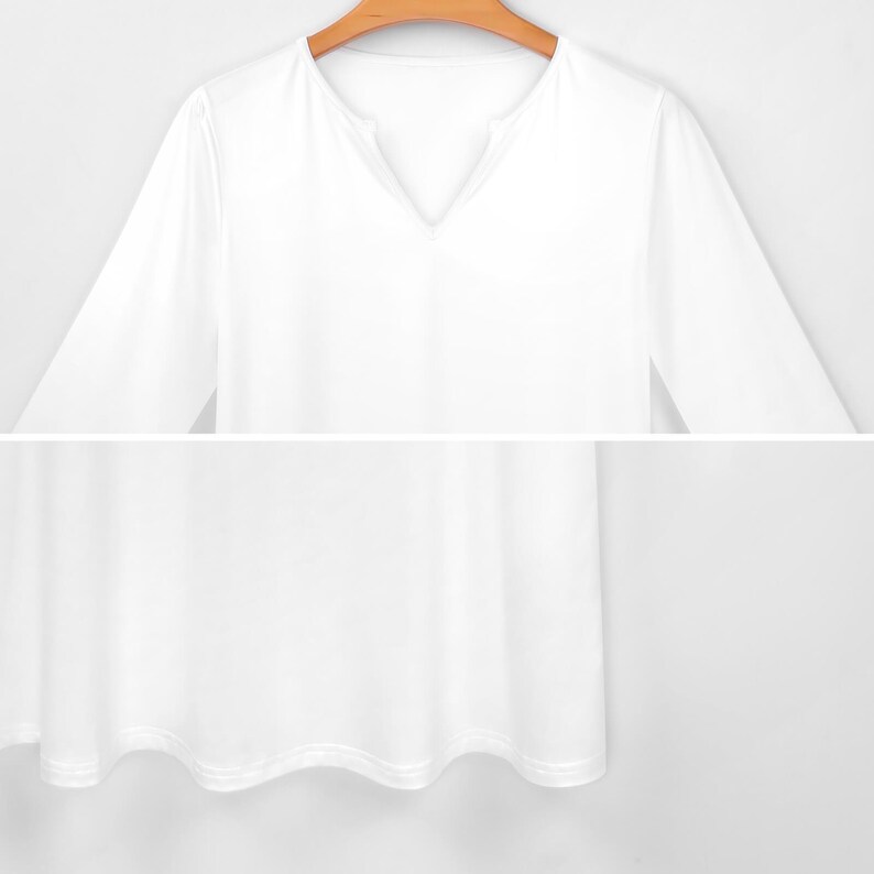May include: A white long-sleeved shirt with a V-neck collar. The shirt is made of a soft, flowing fabric and hangs loosely. The hemline has a subtle wave pattern. The shirt is hanging on a wooden hanger.