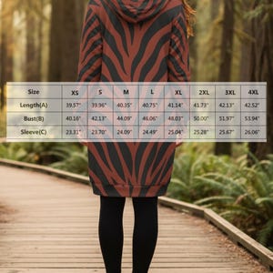 Peut inclure: Robe &agrave; capuche avec un motif &agrave; rayures z&eacute;br&eacute;es marron et noir. La robe arrive au genou et a des manches longues. L'image comprend un tableau des tailles avec des mesures en centim&egrave;tres pour la longueur, le buste et les manches.