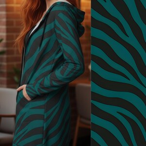 Peut inclure: Une longue veste &agrave; capuche avec un motif z&eacute;br&eacute; teal et noir. La veste a une fermeture &eacute;clair et des poches. Le mod&egrave;le porte un t-shirt blanc en dessous. La veste est faite d'une mati&egrave;re douce et confortable.