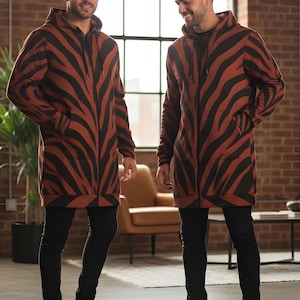 Peut inclure: Une tasse en c&eacute;ramique blanche avec une anse noire et le texte "But First, Coffee" en gras noir. La tasse est pos&eacute;e sur un fond flou, soulignant son design &eacute;pur&eacute;.