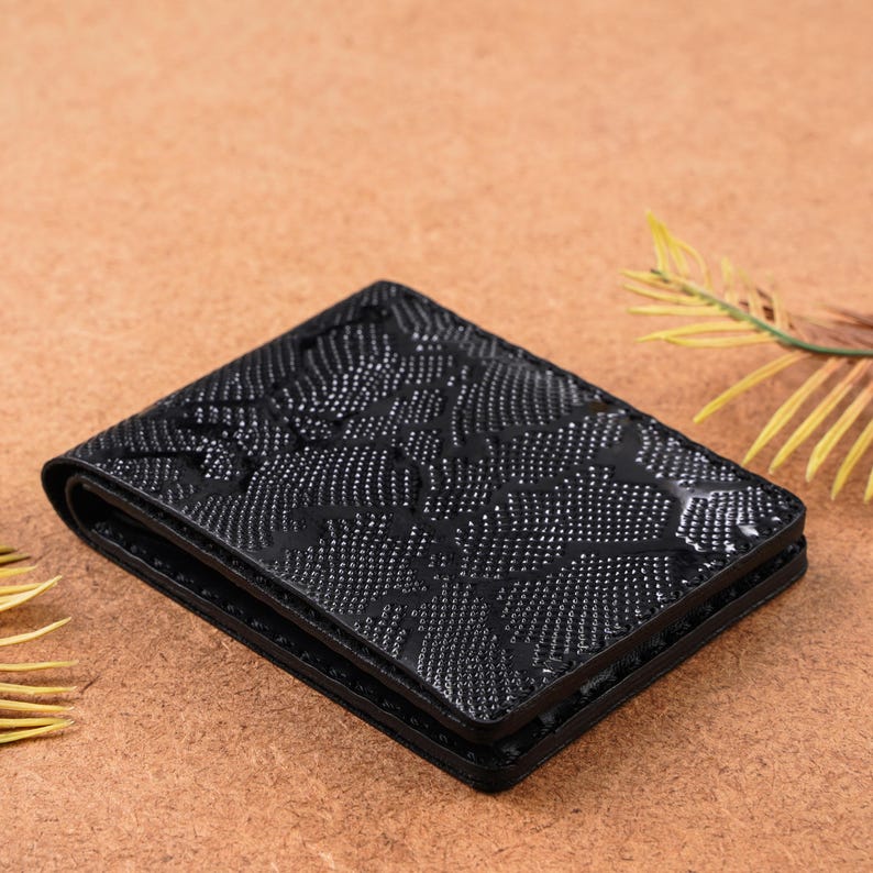 Close-up view of handmade black python pattern leather wallet showing detailed snakeskin-inspired texture. High-quality leather craftsmanship with an exotic finish. Slim bifold design with intricate embossed pattern ideal for men’s luxury fashion, everyday carry, or thoughtful gifts like anniversary, birthday, or groomsmen wallet.