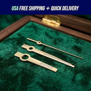 May include: Gold-toned watch hands displayed on a green velvet surface inside a wooden box. The hands include a second hand and two larger hands with a rectangular design. The text "USA FREE SHIPPING + QUICK DELIVERY" is at the top.