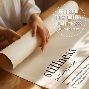 a person's hands holding a roll of paper, with the word "Stillness" printed on it.