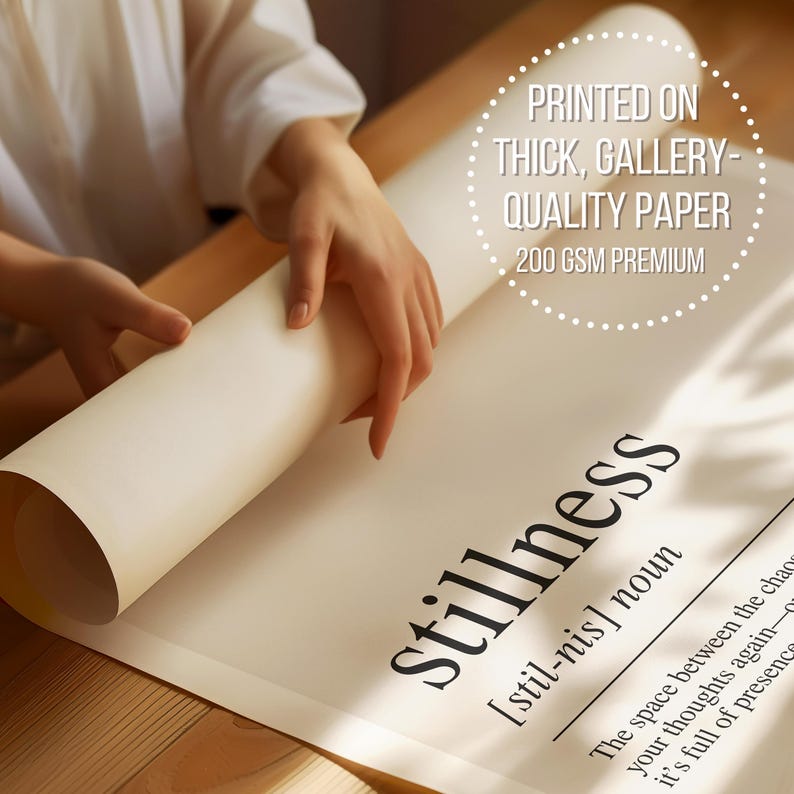a person's hands holding a roll of paper, with the word "Stillness" printed on it.