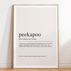 Può includere: Stampa incorniciata con la parola "peekapoo" in grassetto nero. La definizione e i termini correlati sono in basso. La stampa ha uno sfondo beige chiaro ed è incorniciata in una cornice di legno.