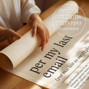 A person's hands are holding a roll of paper with the text "per my email" printed on it, indicating that the paper is printed on thick, gallery-quality paper.