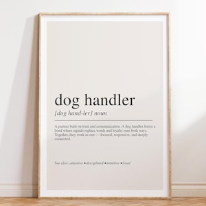 Puede incluir: Un cuadro decorativo con una definición de diccionario para el sustantivo dog handler. El texto está impreso en negro sobre un fondo beige claro, describiendo el rol como un socio basado en la confianza, la comunicación y la lealtad.