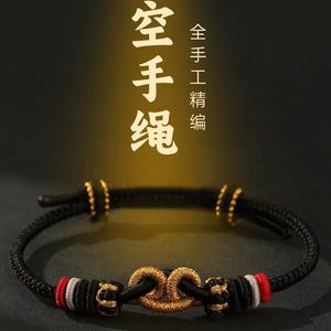 May include: Black braided bracelet with gold accents and a central knot design. The bracelet features red and white details. The image includes Chinese characters and the phrase "Handmade".