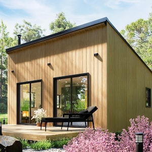 Peut inclure: Une cabane en bois moderne avec un toit noir et de grandes portes vitrées. La cabane dispose d'une terrasse avec une chaise longue noire et est entourée de verdure et de buissons à fleurs roses. La scène se déroule dans un environnement naturel en plein air.