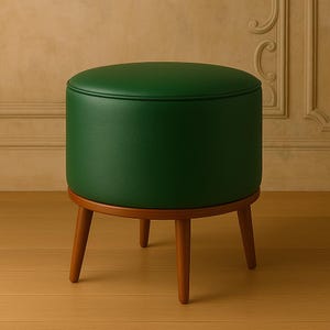 May include: A green upholstered ottoman with a wooden base and four legs. The ottoman is sitting on a wooden floor.