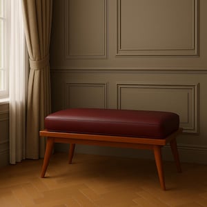 Puede incluir: Un banco tapizado en color burdeos con estructura de madera y patas c&oacute;nicas. El banco est&aacute; sobre un suelo de madera.