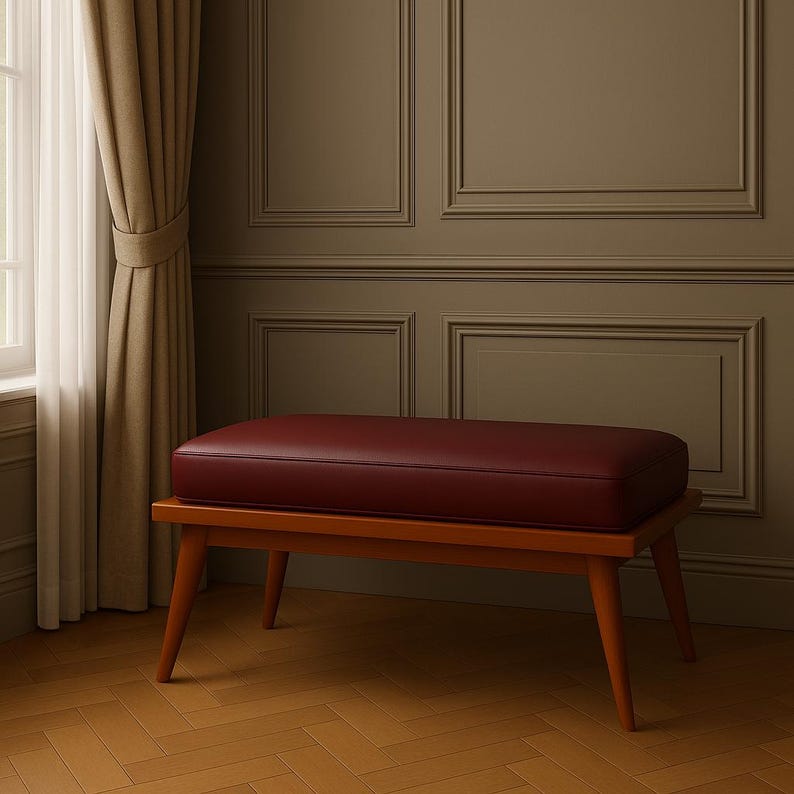 Puede incluir: Un banco tapizado en color burdeos con estructura de madera y patas c&oacute;nicas. El banco est&aacute; sobre un suelo de madera.