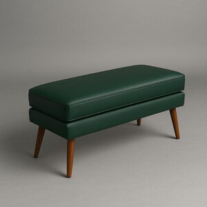 May include: A dark green upholstered bench with a rectangular seat and four wooden legs. The bench has a mid-century modern design. The legs are angled and made of a light brown wood. The bench is approximately 48 inches long.
