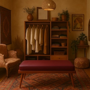 Puede incluir: Un banco de madera con un coj&iacute;n burdeos se encuentra delante de un armario de madera con estantes y ropa colgada. El armario est&aacute; en una habitaci&oacute;n con una alfombra estampada, una silla y una mesa peque&ntilde;a con una planta en maceta.