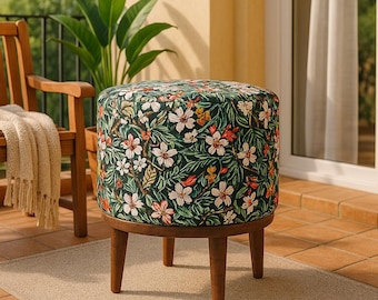 Könnte beinhalten: Ein runder Hocker mit floralem Muster und Holzbeinen. Der Hocker hat einen dunkelgrünen Hintergrund mit weißen, rosa und roten Blumen.