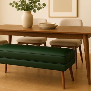 May include: A wooden dining table with four chairs and a green bench. A vase with greenery and two bowls are on the table. The chairs and bench have wooden legs. The room has a neutral color palette.